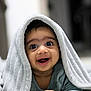 Christian is registered to the contest to win money with this photo: baby, towel, smiling, happy, infant, face, cute, portrait, child, indoors, cozy, blanket, expression, hands, lying_down, skin, eyes, clothing, head, closeup