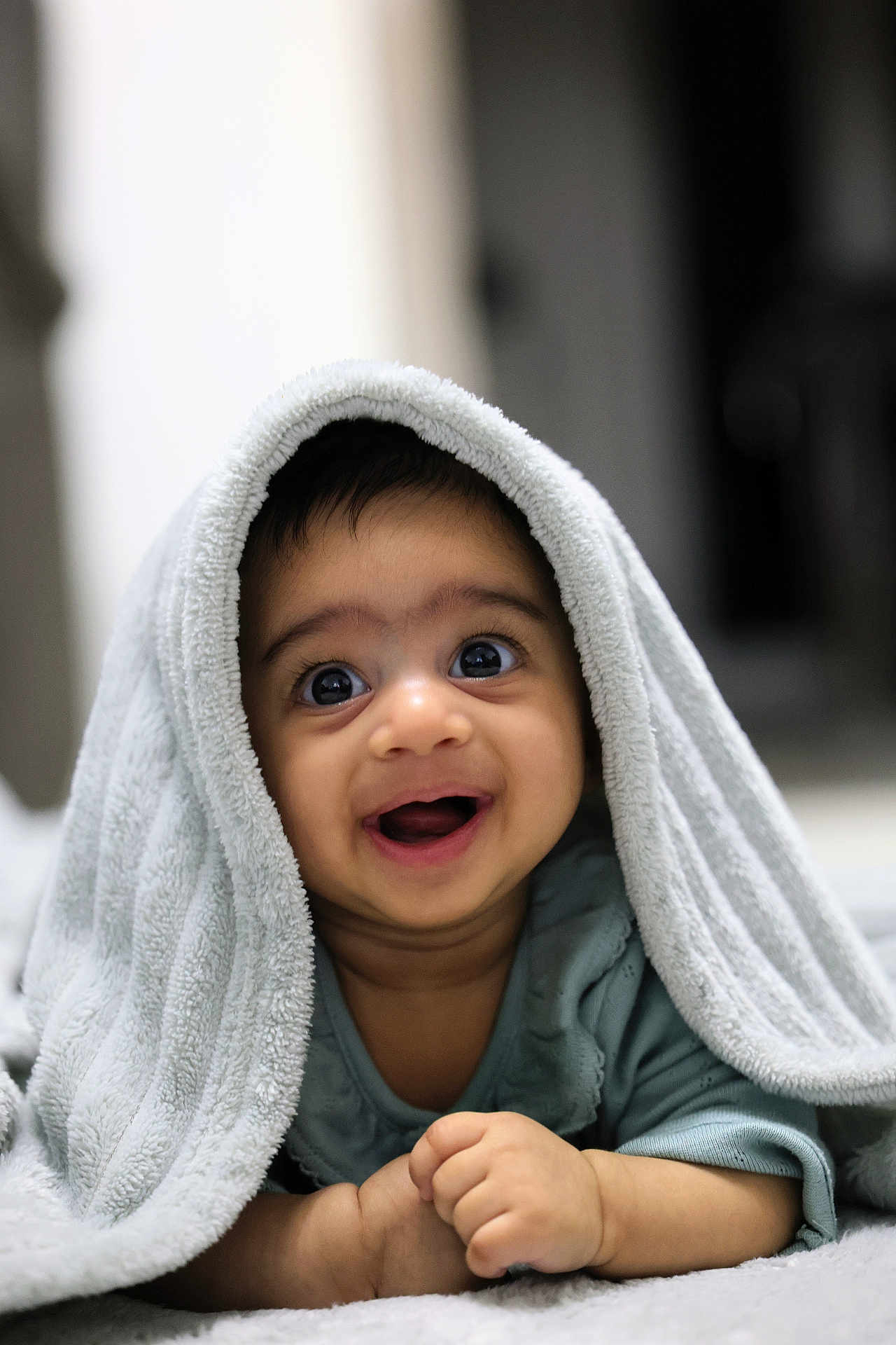 Christian is registered to the contest to win money with this photo: baby, towel, smiling, happy, infant, face, cute, portrait, child, indoors, cozy, blanket, expression, hands, lying_down, skin, eyes, clothing, head, closeup