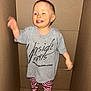 toddler, child, cardboard_box, smiling, standing, indoors, clothing, striped_pants, grey_tshirt, happy, person, cute, playful, sock, one_child, face, young_child, casual_wear, fun, joyful