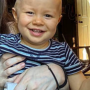 Atticus is registered to the contest to win money with this photo: toddler, child, smiling, striped_shirt, mohawk, indoor, hand, adult, door, sunlight, furniture, happy, face, person, portrait, holding, casual, home, cute, baby