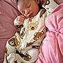 baby, sleeping, onesie, teddy_bear_pattern, pink_cushion, infant, soft, cozy, cute, child, resting, face, hand, clothing, bed, pillow, comfort, peaceful, newborn, portrait