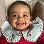 baby, smile, happy, infant, red_clothing, ruffled_collar, heart_pattern, face, portrait, cute, sitting, quilted_background, child, closeup, young_child, indoors, person, skin, eyes, mouth