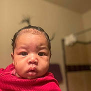 Maliyah joined the competition — help win amazing prizes! baby, blurry_background, child, curly_hair, cute, expression, eyebrows, face, hair, hand, holding, indoor, lips, nostrils, person, portrait, red_clothing, room, skin, young_child