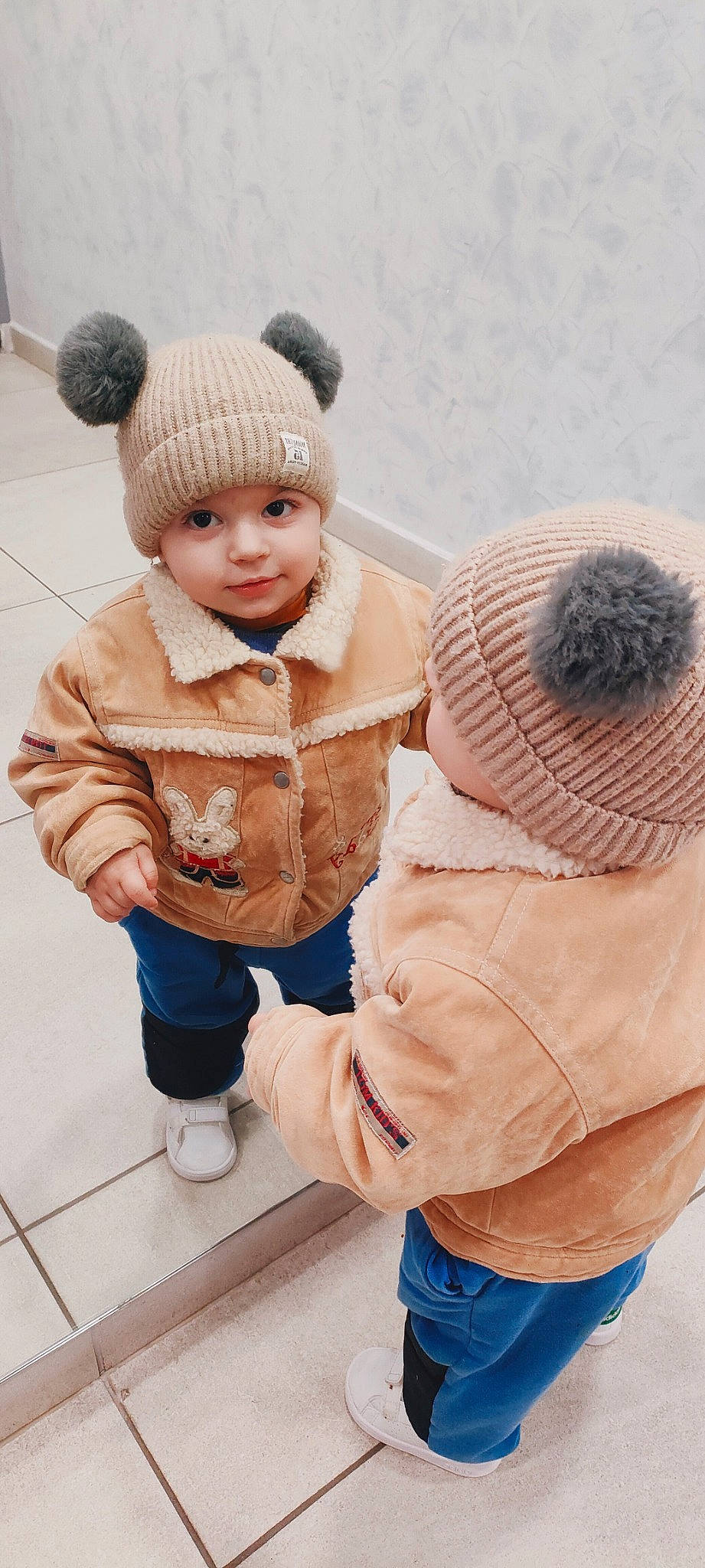 Leonidas participe au concours pour gagner de l'argent avec cette photo : baby, baby_toddler_clothing, cap, child, clothing, flooring, happy, headgear, headwear, jacket, knit_cap, outerwear, person, photograph, shoe, skin, sleeve, smile, textile, toddler