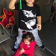 Andy joined the competition — help win amazing prizes! children, child, toddler, sibling, standing, sitting, indoors, portrait, smiling, toy, green_toy, red_outfit, shark_shirt, curly_hair, wood_floor, folding_chair, playtime, family, casual_clothing, home