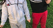 Andy is registered to the contest to win money with this photo: children, child, smiling, outdoor, grass, dog, pet, cuddling, portrait, siblings, casual_clothing, hoodie, tracksuit, red_pants, black_shoes, sunlight, backyard, fence, standing, happy