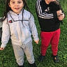 children, child, smiling, outdoor, grass, dog, pet, cuddling, portrait, siblings, casual_clothing, hoodie, tracksuit, red_pants, black_shoes, sunlight, backyard, fence, standing, happy