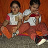 children, child, sibling, kids, portrait, sitting, carpet, indoors, orange_background, handheld_device, video_game, red_device, sneakers, shoes, casual_clothing, smiling, braids, family, photography, playtime