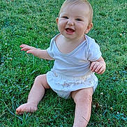 Lina-Maria participe au concours pour gagner de l'argent avec cette photo : baby, child, grass, outdoor, smiling, happy, sitting, nature, greenery, sunlight, skirt, white_top, barefoot, cute, infant, playful, person, head, face, summer