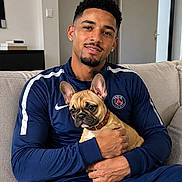 Boubou a rejoint le concours — aidez-le/la à gagner de superbes lots ! animal, blue_tracksuit, casual_clothing, comfort, couch, cute, dog, french_bulldog, home, indoor, living_room, man, modern_interior, person, pet, portrait, puppy, relaxed, seated, smiling