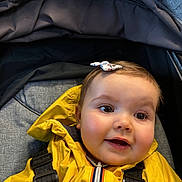 Garance participe au concours pour gagner de l'argent avec cette photo : baby, child, yellow_jacket, stroller, bow, smiling, face, young_child, happy, cute, infant, outerwear, straps, closeup, person, portrait, headwear, seat, fabric, indoors
