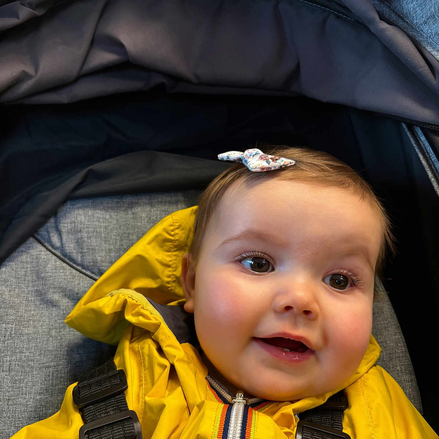 Garance participe au concours pour gagner de l'argent avec cette photo : baby, bow, child, closeup, cute, fabric, face, happy, headwear, indoors, infant, outerwear, person, portrait, seat, smiling, straps, stroller, yellow_jacket, young_child