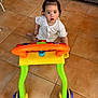 Estella participe au concours pour gagner de l'argent avec cette photo : toddler, child, toy, walker, indoor, floor, tile, curious, playful, sitting, hair_tie, white_clothing, plastic, colorful, wheels, young_child, person, baby, cute, looking_up