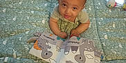 Enoa participe au concours pour gagner de l'argent avec cette photo : baby, child, play_mat, toy, book, dinosaur, floor, mirror, carpet, indoor, clothing, infant, cute, smiling, looking_up, soft_toy, patterned, toddler, hands, face