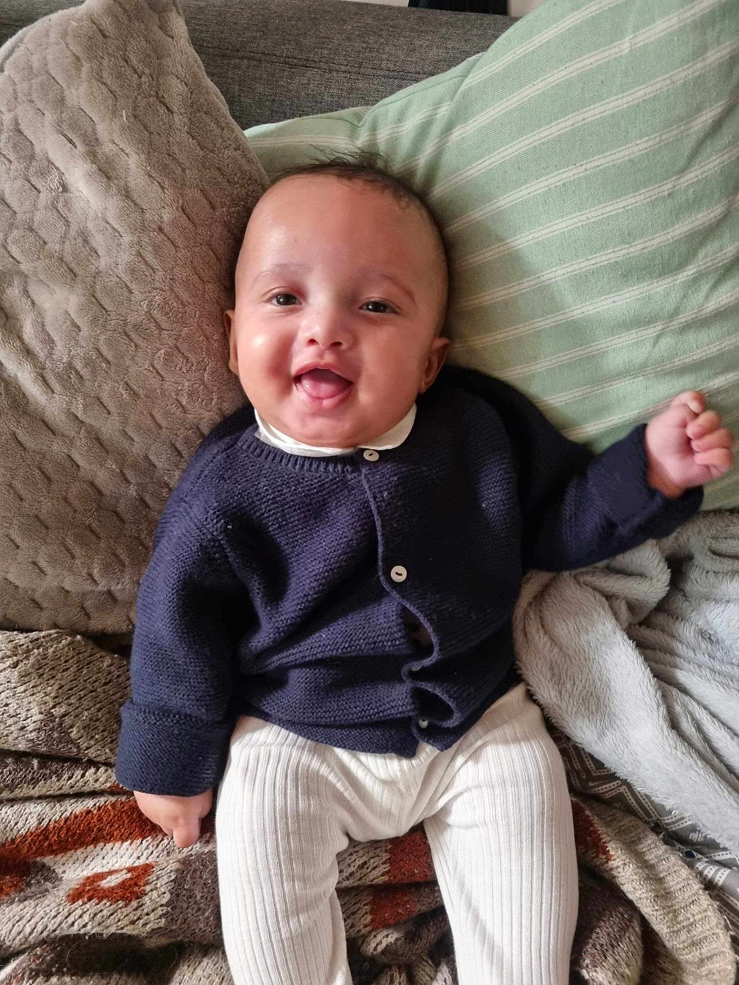 Enoa participe au concours pour gagner de l'argent avec cette photo : baby, smiling, sitting, navy_sweater, white_pants, pillow, blanket, cozy, indoors, cute, child, happy, face, person, infant, soft, comfort, home, portrait, warm