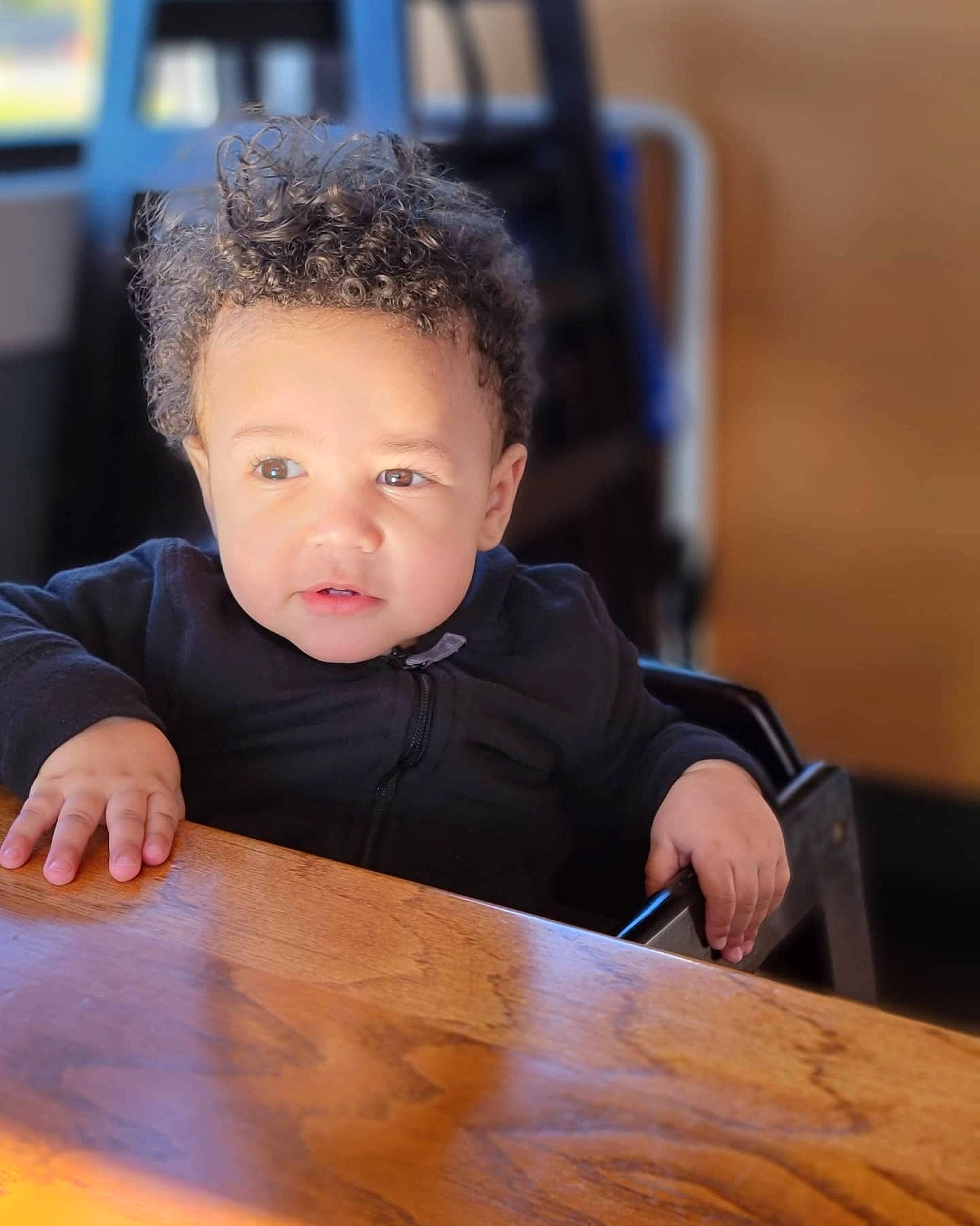 Arthur is registered to the contest to win money with this photo: black_hair, chair, cheek, child, chin, eye, finger, flash_photography, flooring, fun, happy, hardwood, leisure, nose, person, sitting, table, toddler, varnish, wood