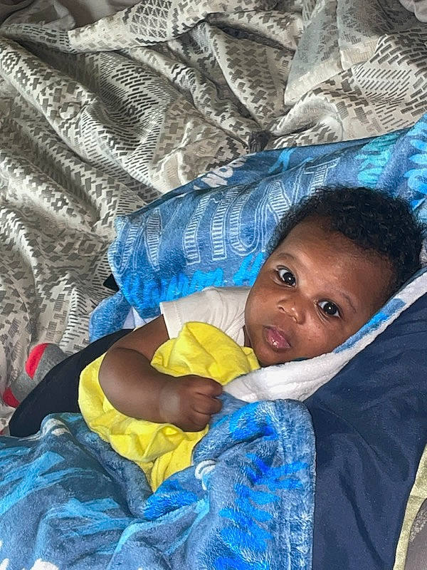 Kauron is registered to the contest to win money with this photo: azure, baby, beauty, child, comfort, electric_blue, eye, fun, grass, happy, human, leisure, linens, pattern, person, sitting, skin, textile, toddler, tree