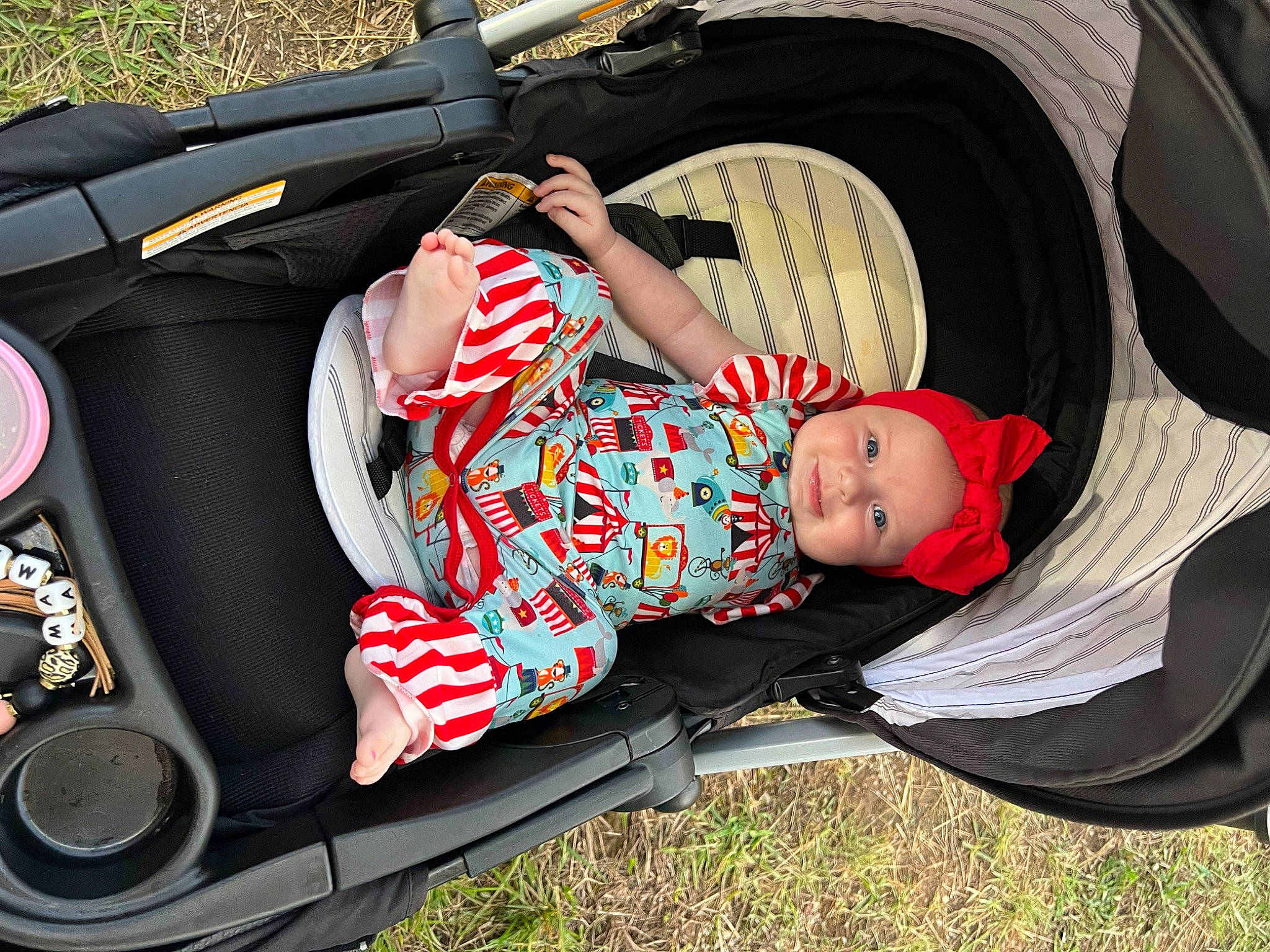 Hattie is registered to the contest to win money with this photo: auto_part, automotive_design, automotive_exterior, automotive_lighting, baby, baby_carriage, baby_products, bag, car_seat, child, comfort, fashion_accessory, grass, headwear, luggage_and_bags, motor_vehicle, person, recreation, sitting, toddler