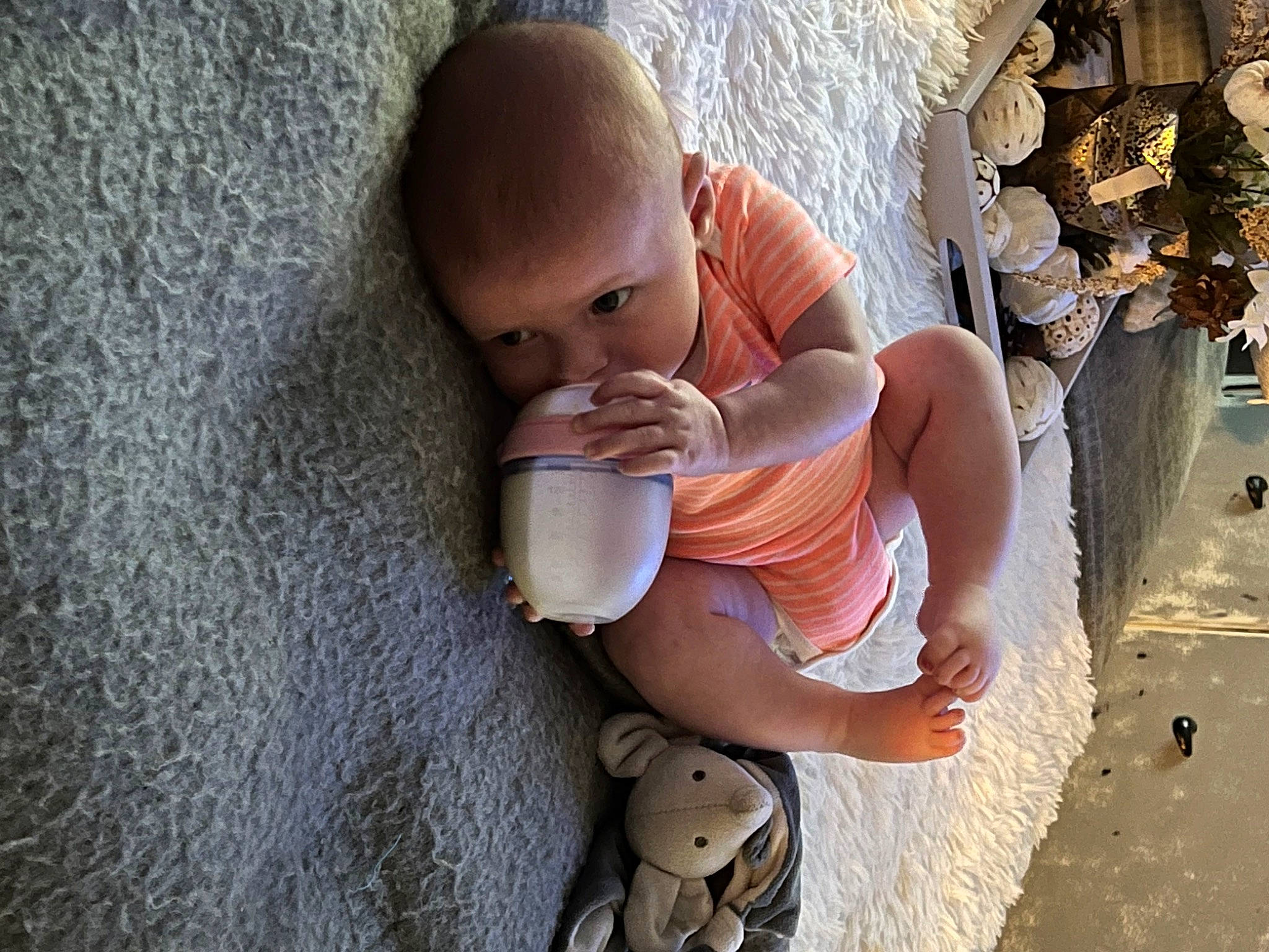 Hattie is registered to the contest to win money with this photo: abdomen, arm, baby, baby_products, chest, child, drinking, elbow, finger, fun, hand, human_leg, nail, person, personal_protective_equipment, sitting, skin, toddler, toy, vacation