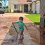 Kosei is registered to the contest to win money with this photo: child, toddler, water_hose, water_splash, wet_clothes, barefoot, driveway, house, residential, sunny_day, outdoor, green_lawn, palm_trees, summer, play, fun, person, water, garden_hose, casual_clothing