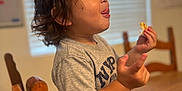 Kosei joined the competition — help win amazing prizes! toddler, child, curly_hair, gray_shirt, nypd, snacking, tongue_out, playful, indoor, wooden_chair, wooden_table, plate, food, window_blinds, home, person, cute, casual, portrait, happy
