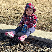Aera is registered to the contest to win money with this photo: casual_clothing, child, cute, daytime, face, grass, hoodie, nature, outdoor, park, pink_shoes, plaid, red, sidewalk, sitting, snack, sunlight, toddler, wood_chips, young_child