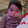Aera is registered to the contest to win money with this photo: child, toddler, indoor, person, face, clothing, hand, window, ceiling, architecture, modern, ribbed_fabric, holding, serious_expression, red_text, shirt, light, large_space, portrait, baby