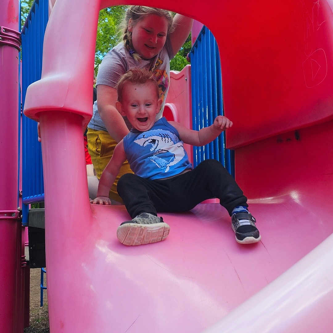 Sylar is registered to the contest to win money with this photo: braids, child, clothing, daylight, fun, greenery, happy, outdoor, park, person, pink_slide, play, playground, recreation, slide, smiling, sneakers, summer, toddler, youth
