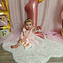 baby, girl, pink_dress, headband, balloon, number_one, birthday, celebration, fluffy_rug, wooden_floor, golden_crown, blocks, letters, curtains, fairy_lights, smiling, sitting, indoor, decorations, first_birthday