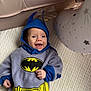 Rowan joined the competition — help win amazing prizes! baby, child, batman_costume, blue_hood, cape, smile, happy, infant, costume, superhero, pillow, stars, white_background, cute, portrait, lying_down, soft_texture, indoor, playful, clothing