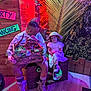 child, man, dinosaur_puppet, crate, wooden_box, white_dress, safari_hat, boots, neon_lights, tropical_decor, palm_leaves, wooden_wall, flooring, face_paint, indoor, people, smile, toy, fun, posing