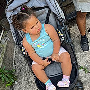 Logann joined the competition — help win amazing prizes! baby, casual_clothing, child, concrete, crocs, curly_hair, cute, expression, footwear, hair_ties, legs, mismatched_socks, outdoor, person, seatbelt, side_view, stroller, sunlight, tank_top, toddler