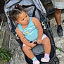 baby, casual_clothing, child, concrete, crocs, curly_hair, cute, expression, footwear, hair_ties, legs, mismatched_socks, outdoor, person, seatbelt, side_view, stroller, sunlight, tank_top, toddler