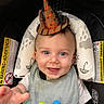 Thayer is registered to the contest to win money with this photo: baby, infant, child, smiling, party_hat, birthday, high_chair, car_seat, toy, colorful_toy, bib, blue_eyes, portrait, sitting, indoor, happy, reaching, playful, cushion, safety_warning