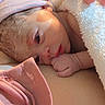 adorable, baby, blanket, close_up, clothing, cozy, cuddly, eyes, face, fist, hand, hat, indoors, infant, lying_down, newborn, pink, portrait, sleepy, soft_lighting