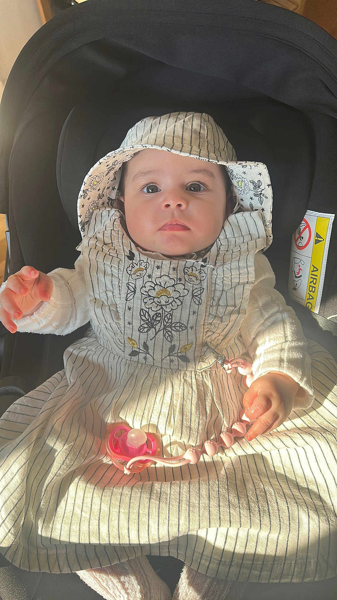 Lyna a rejoint le concours — aidez-le/la à gagner de superbes lots ! baby, infant, car_seat, sunhat, dress, stripes, pacifier, pacifier_clip, hands, eyes, adorable, portrait, sunlight, shadow, fabric, seat, safety_label, buckle, hood, closeup