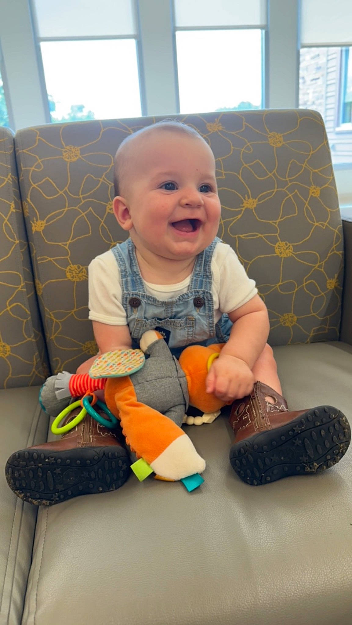 Dallas is registered to the contest to win money with this photo: baby, baby_playing_with_toys, baby_toddler_clothing, cheek, child, comfort, couch, floor, flooring, fun, happy, joy, living_room, person, room, sitting, skin, smile, sock, toddler