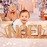Eliano a rejoint le concours — aidez-le/la à gagner de superbes lots ! baby, child, smile, holiday, christmas, noel, wooden_letters, star, teddy_bear, decorations, candles, festive, indoors, soft_surface, happy, portrait, cute, seasonal, celebration, background