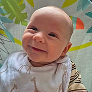Oscar is registered to the contest to win money with this photo: baby, smiling, infant, bib, giraffe_pattern, clothing, face, child, happy, cheeky, indoor, seat, highchair, striped_sleeve, cute, young, person, portrait, head, expression