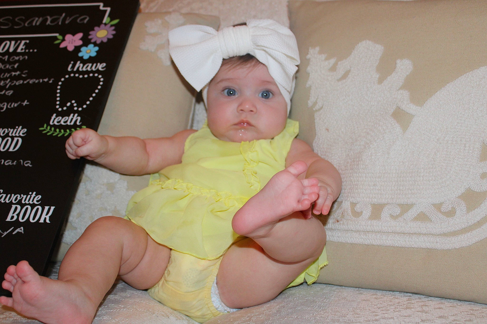 Kassandra is registered to the contest to win money with this photo: baby, baby_toddler_clothing, cheek, child, comfort, facial_expression, finger, foot, gesture, hand, headwear, human_body, human_leg, knee, lap, person, pink, sitting, skin, thigh