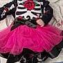baby, infant, tutu, pink_skirt, skeleton_outfit, red_rose, black_shoes, white_shoes, patterned_socks, lying_down, blanket, bow, cute, child, fashion, footwear, clothing, portrait, indoors, soft_toys