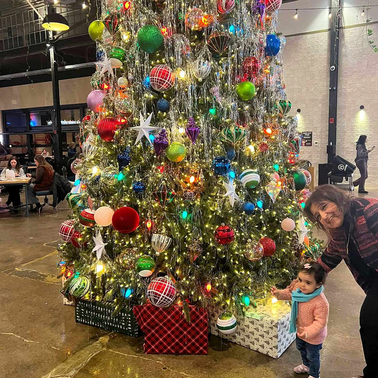 Sophia joined the competition — help win amazing prizes! celebration, chairs, child, christmas_tree, curious, decorations, elderly_woman, festive, floor, holiday, indoor, lights, ornaments, people, presents, scarf, smile, sweater, table, toddler