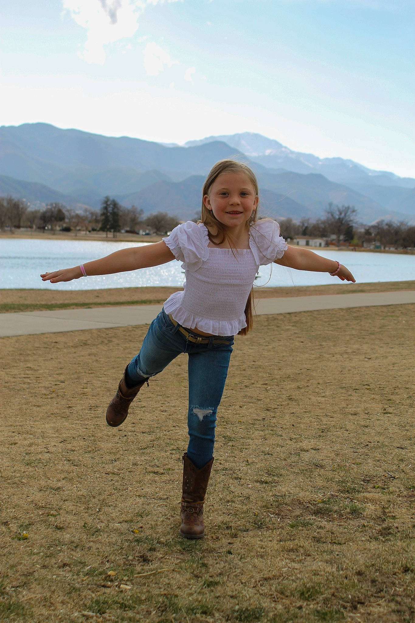 Delaney is registered to the contest to win money with this photo: cloud, ecoregion, flash_photography, fun, gesture, grassland, happy, horizon, joy, knee, lake, landscape, leisure, long_hair, mountain, people_in_nature, person, recreation, sky, travel