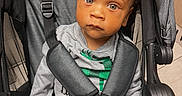 Emerson is registered to the contest to win money with this photo: child, toddler, stroller, baby, seatbelt, blanket, red, gray, clothing, indoor, face, person, expression, curious, looking, sitting, head, hair, safety, toy