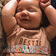 Nalani joined the competition — help win amazing prizes! baby, smiling, arms_up, infant, sleeping, shirt, text_on_clothing, strap, rainbow, unicorn, closeup, cozy, indoor, resting, cute, child, peaceful, person, portrait, soft_lighting