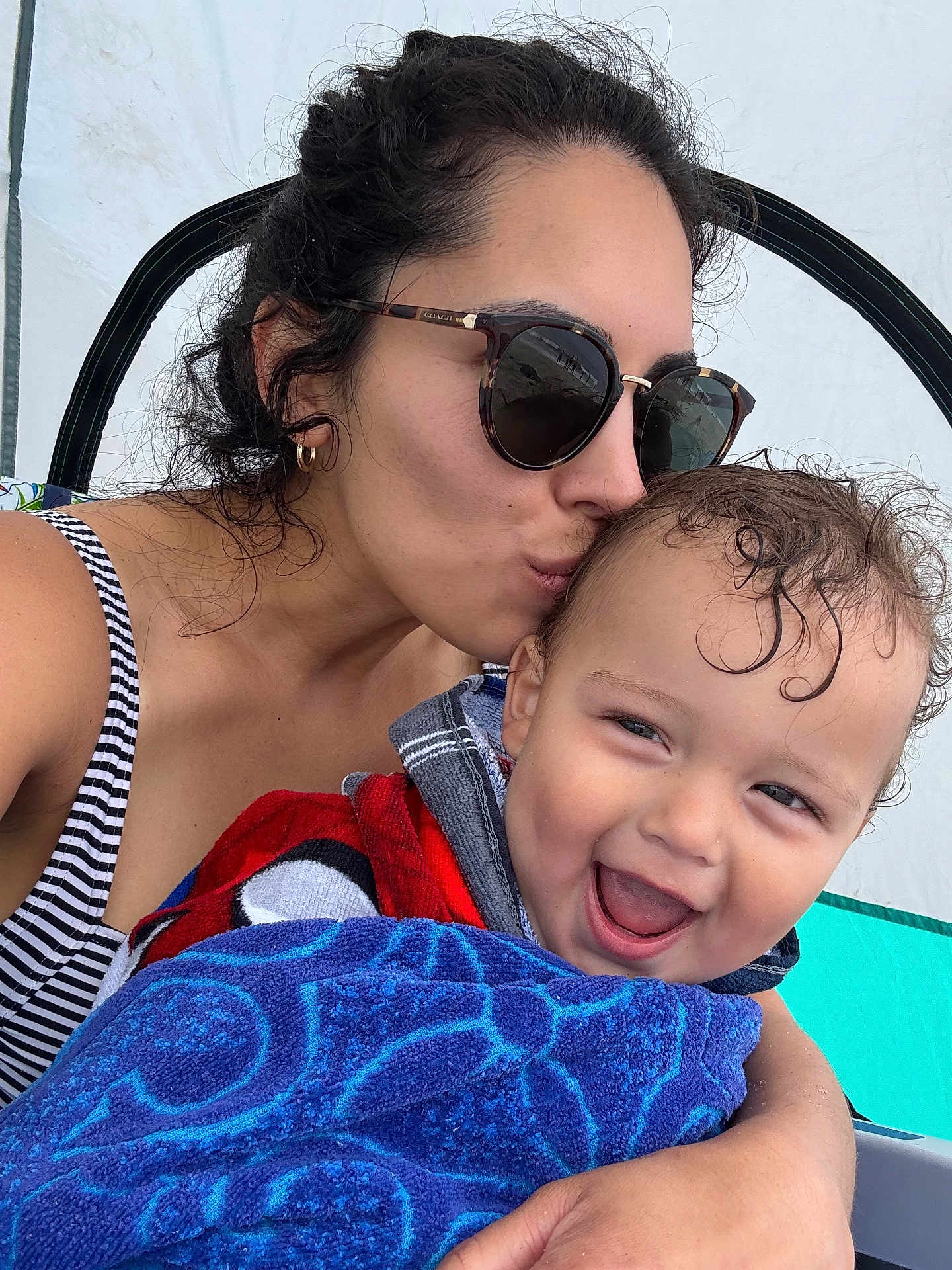 Benjamin is registered to the contest to win money with this photo: woman, toddler, child, sunglasses, kiss, smile, happy, towel, striped_clothing, outdoor, tent, affection, hair, skin, face, person, summer, vacation, closeup, playful