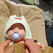 Rachid participe au concours pour gagner de l'argent avec cette photo : baby, pacifier, towel, blanket, hands, infant, hooded_towel, blue_pacifier, soft_texture, baby_wipes, clothing, floor, indoor, cute, child, person, skin, wrapping, newborn, care