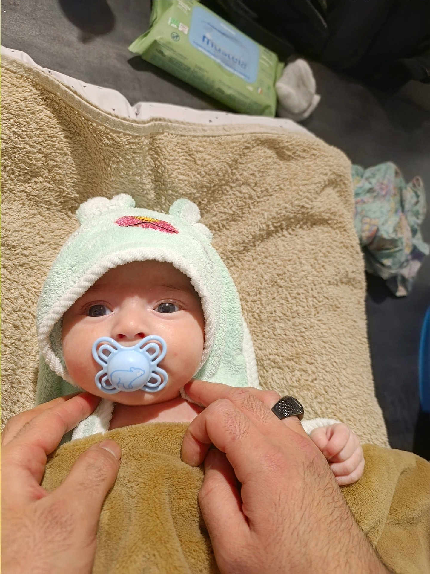 Rachid participe au concours pour gagner de l'argent avec cette photo : baby, pacifier, towel, blanket, hands, infant, hooded_towel, blue_pacifier, soft_texture, baby_wipes, clothing, floor, indoor, cute, child, person, skin, wrapping, newborn, care