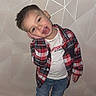 child, boy, plaid_shirt, jeans, white_tshirt, smiling, pose, standing, indoor, wooden_floor, geometric_wall, casual_clothes, happy, short_hair, playful, person, portrait, full_body, fashion, cute