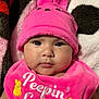 baby, infant, pink_hat, bunny_ears, bib, pink_bib, cute, face, cheeks, expression, soft_blanket, yellow_bunny, clothing, headwear, portrait, closeup, child, adorable, indoor, baby_fashion